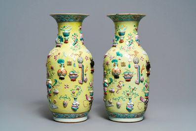 A pair of Chinese yellow-ground famille rose relief-decorated vases, 19th C.