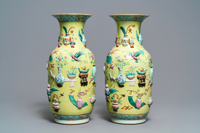 A pair of Chinese yellow-ground famille rose relief-decorated vases, 19th C.