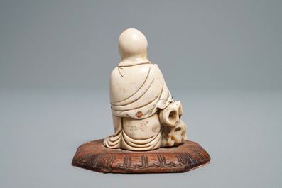 A Chinese inlaid soapstone figure of a seated deity, 17/18th C.