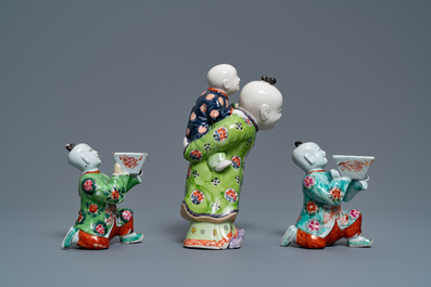 A pair of Chinese blue and white candlesticks and three famille rose figures of boys, 19th C.