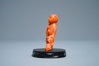 A Chinese carved red coral group of a boy with a dog, 20th C.