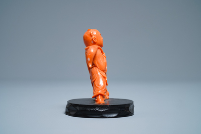 A Chinese carved red coral group of a boy with a dog, 20th C.