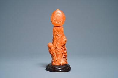 A Chinese carved red coral group of Guanyin with child, 19th C.