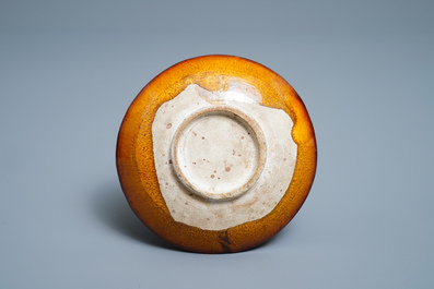 Une assiette en gr&egrave;s porcelaineux &agrave; couverte ambre &agrave; d&eacute;cor en relief, Liao (916-1125)