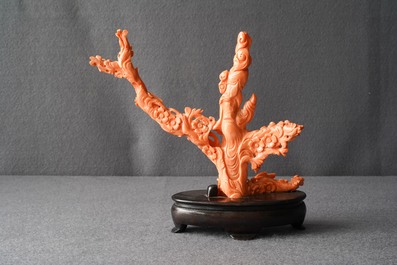 A Chinese carved red coral group of a lady among blossoming branches, 19th C.