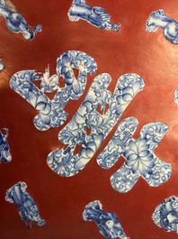 A Chinese red-lacquered plaque with blue and white porcelain inserts, 19/20th C.