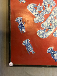 A Chinese red-lacquered plaque with blue and white porcelain inserts, 19/20th C.