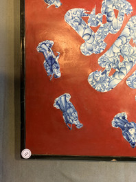 Une plaque laqu&eacute;e rouge incrust&eacute;e de porcelaine de Chine en bleu et blanc, 19/20&egrave;me