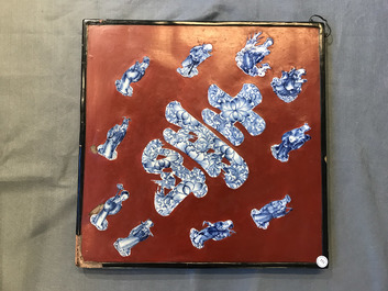 Une plaque laqu&eacute;e rouge incrust&eacute;e de porcelaine de Chine en bleu et blanc, 19/20&egrave;me