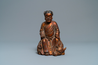 Een Chinese gelakte en vergulde houten figuur van een jongen op een os, 18/19e eeuw