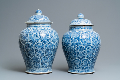 A pair of Chinese blue and white vases and covers with floral design, Kangxi