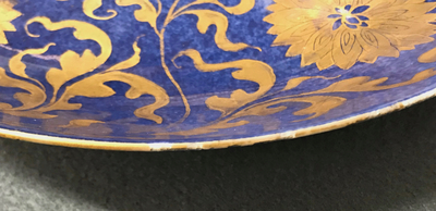 Een Chinese poederblauwe en vergulde schotel met floraal decor, Kangxi