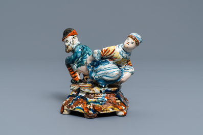 A polychrome Dutch Delft group of a man and a woman on a chamberpot, 18th C.