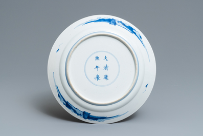 Un plat en porcelaine de Chine en bleu et blanc &agrave; d&eacute;cor de figures dans un int&eacute;rieur, marque et &eacute;poque de Kangxi