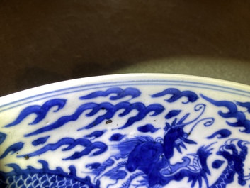 Un plat en porcelaine de Chine en bleu et blanc &agrave; d&eacute;cor d'un dragon, marque et &eacute;poque de Kangxi