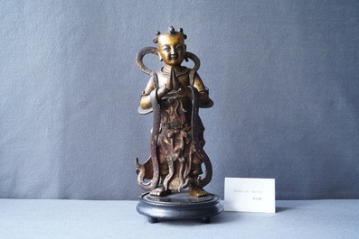 Een Chinese gelakte en vergulde bronzen figuur van een dienaar, Ming