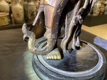 Een Chinese gelakte en vergulde bronzen figuur van een dienaar, Ming