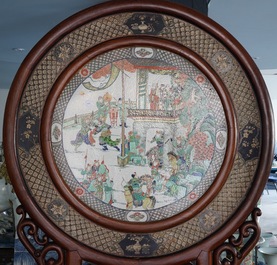 A massive Chinese carved wooden screen with a round famille verte plaque and polychrome lacquer, 19th C.