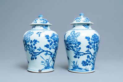 A pair of Chinese blue and white baluster vases and covers with birds in a rocky landscape, Kangxi