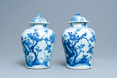 A pair of Chinese blue and white baluster vases and covers with birds in a rocky landscape, Kangxi