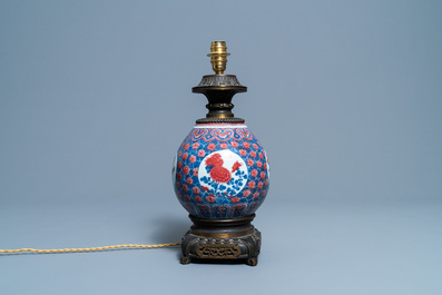 Een Chinese blauw-witte en koperrode vaas met vergulde bronzen lampmontuur, 19e eeuw