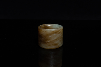 Een Chinese boogschuttersring in gevlekte celadon jade, Ming