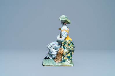 A polychrome Dutch Delft figure of a seated lady, 18th C.