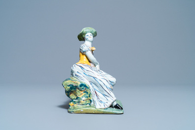 A polychrome Dutch Delft figure of a seated lady, 18th C.