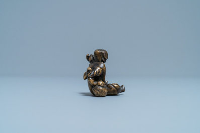Een Chinees bronzen 'Liu Hai' scrollgewicht op houten sokkel, Ming