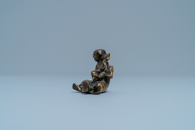 A Chinese bronze 'Liu Hai' scroll weight on wooden stand, Ming