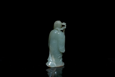 A Chinese carved celadon jade 'immortal' figure on wooden stand, Qing