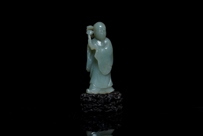 A Chinese carved celadon jade 'immortal' figure on wooden stand, Qing