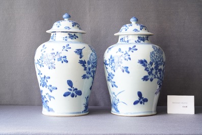 A pair of Chinese blue and white baluster vases and covers with birds in a rocky landscape, Kangxi