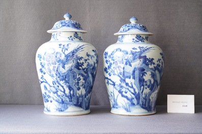 A pair of Chinese blue and white baluster vases and covers with birds in a rocky landscape, Kangxi