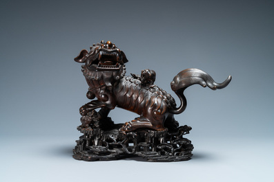 Een Chinees bronzen model van een boeddhistische leeuw op houten sokkel, 18e eeuw