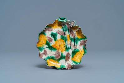 A Chinese 'egg and spinach'-glazed lotus cup and saucer with applied design, Kangxi