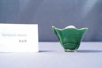 A Chinese 'egg and spinach'-glazed lotus cup and saucer with applied design, Kangxi