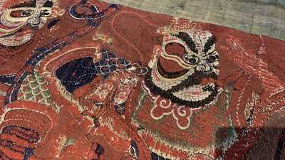 A large Chinese horizontal embroidered red-ground textile panel, 19th C.