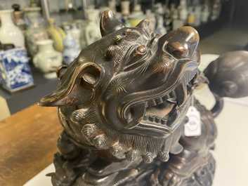 Un mod&egrave;le d'un lion bouddhiste en bronze sur socle en bois sculpt&eacute;, Chine, 18&egrave;me