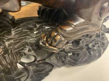 A Chinese bronze model of a Buddhist lion on a finely carved wooden stand, 18th C.