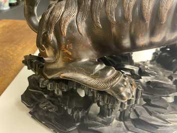 Een Chinees bronzen model van een boeddhistische leeuw op houten sokkel, 18e eeuw