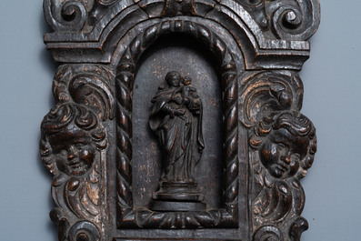 Een gepatineerde houten nis met een Madonna met kind geflankeerd door engelenkopjes, 18e eeuw