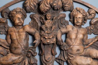 A reticulated carved oak fronton with two winged cherubs holding a horn, France, 17th C.