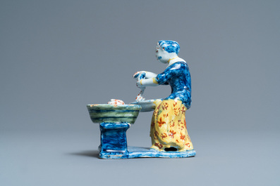 A rare polychrome Dutch Delft figure of a butcher's lady stuffing sausages, 18th C.