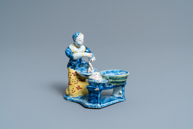 A rare polychrome Dutch Delft figure of a butcher's lady stuffing sausages, 18th C.