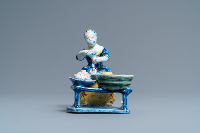 A rare polychrome Dutch Delft figure of a butcher's lady stuffing sausages, 18th C.