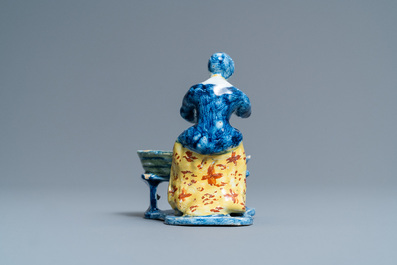 A rare polychrome Dutch Delft figure of a butcher's lady stuffing sausages, 18th C.