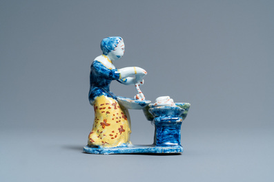 A rare polychrome Dutch Delft figure of a butcher's lady stuffing sausages, 18th C.