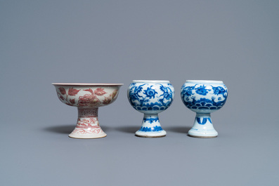 Une paire de bols sur piedouche en porcelaine de Chine en bleu et blanc et un en rouge de cuivre, 19/20&egrave;me