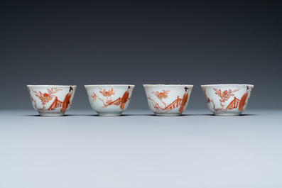 Four Chinese iron-red and gilt cups and saucers with figures near a table, Kangxi